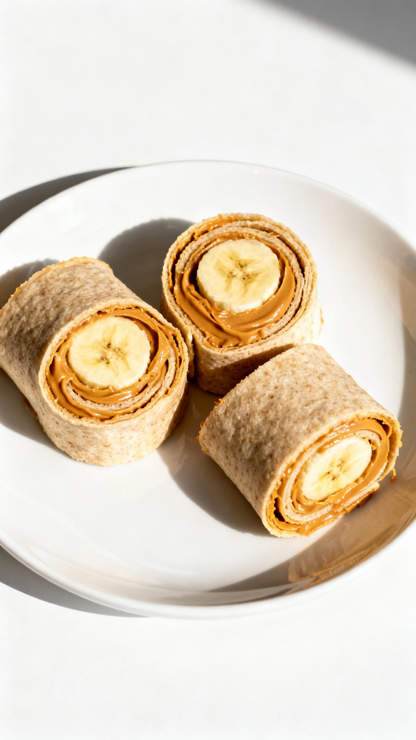 peanut butter banana roll-ups on white plate, overhead