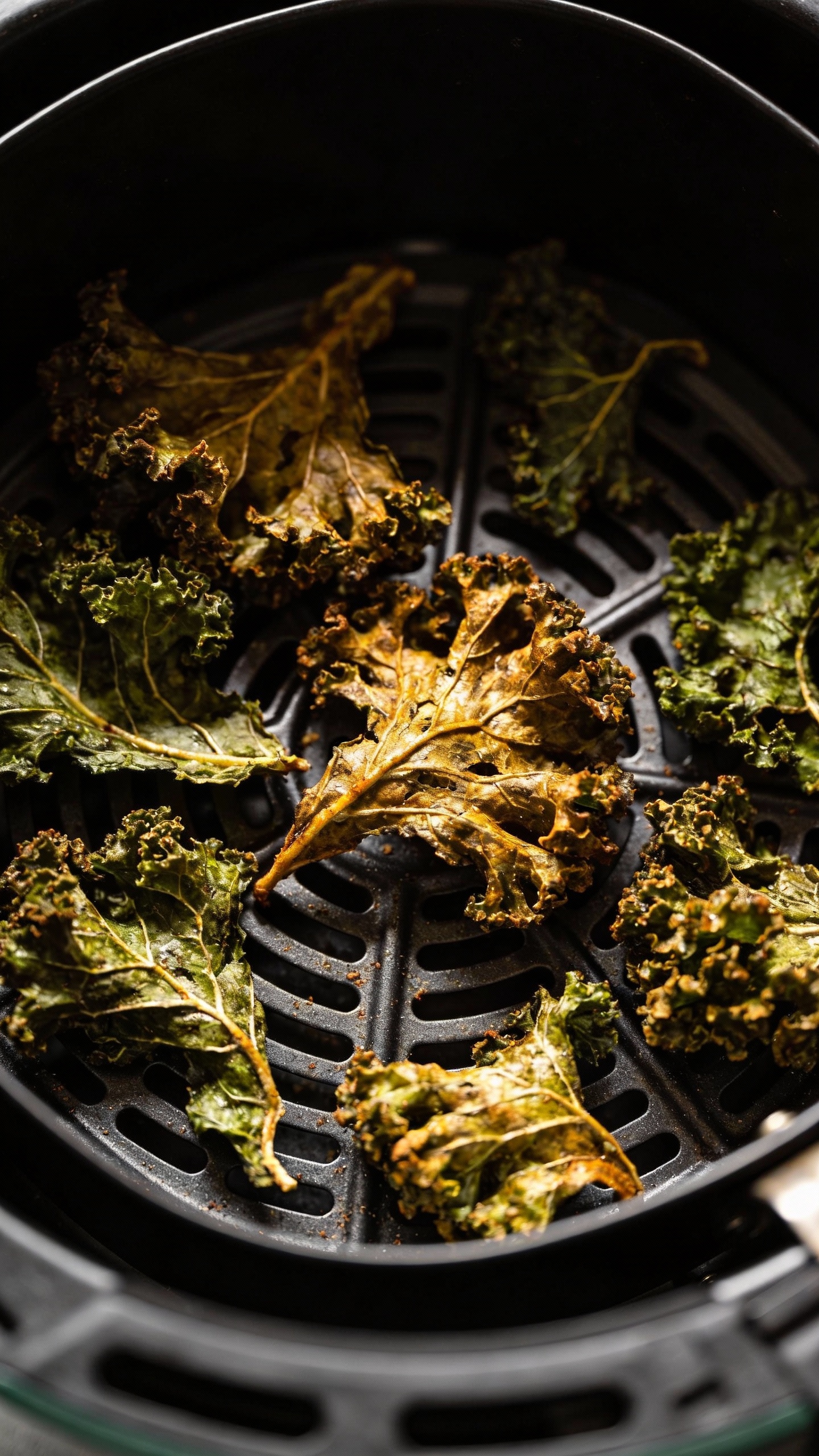 air fryer basket with crispy kale chips, overhead, moody lighting