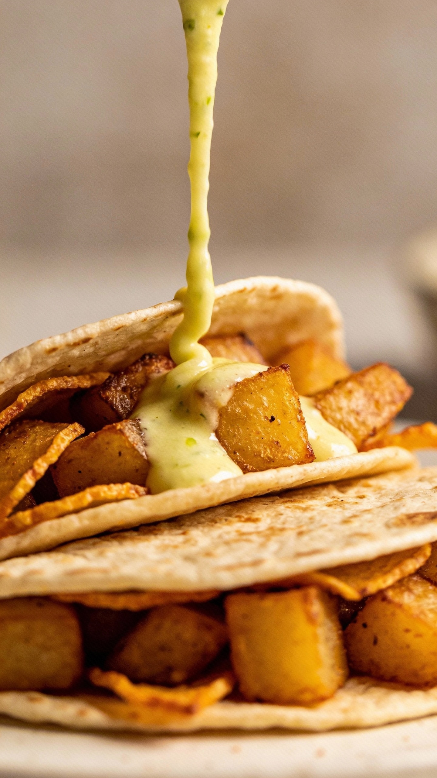 warm tortillas filled with crispy potatoes, lime crema drizzle