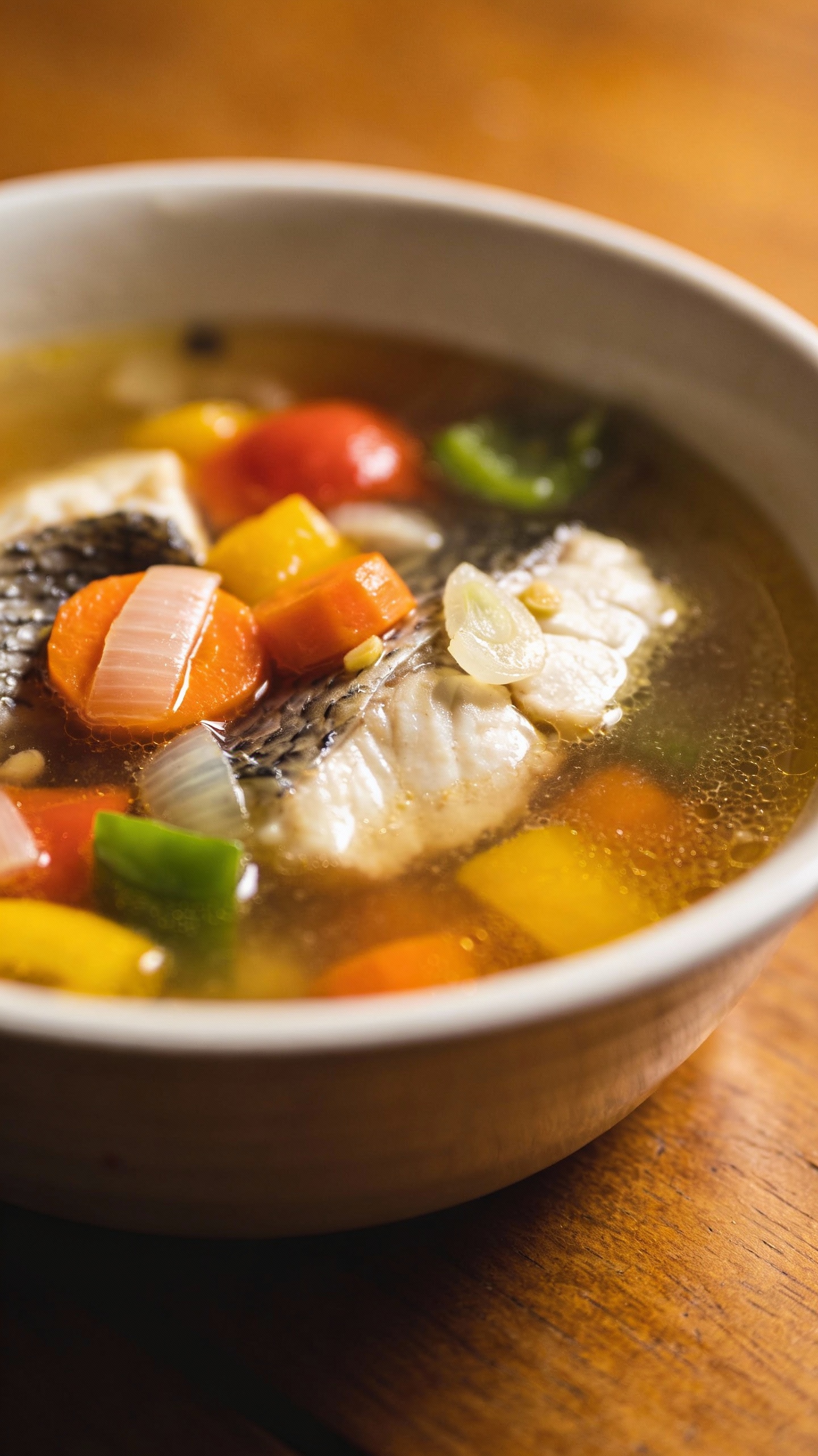 Slow cooker fish stew in white bowl, brothy, colorful vegetables