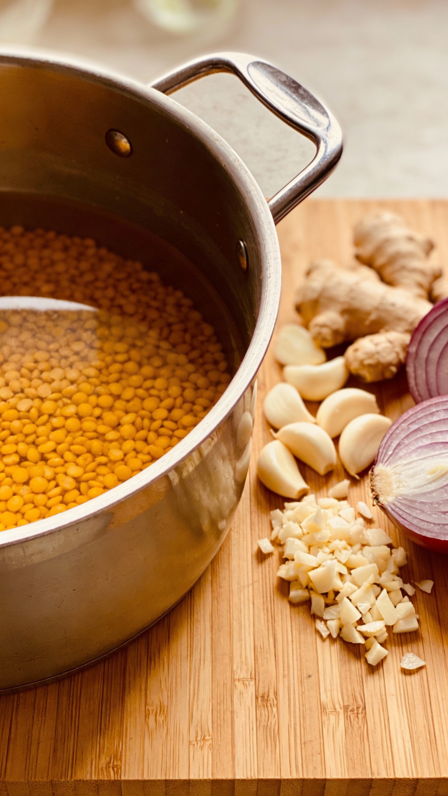 chopped garlic, ginger, onions beside pot of turmeric lentils