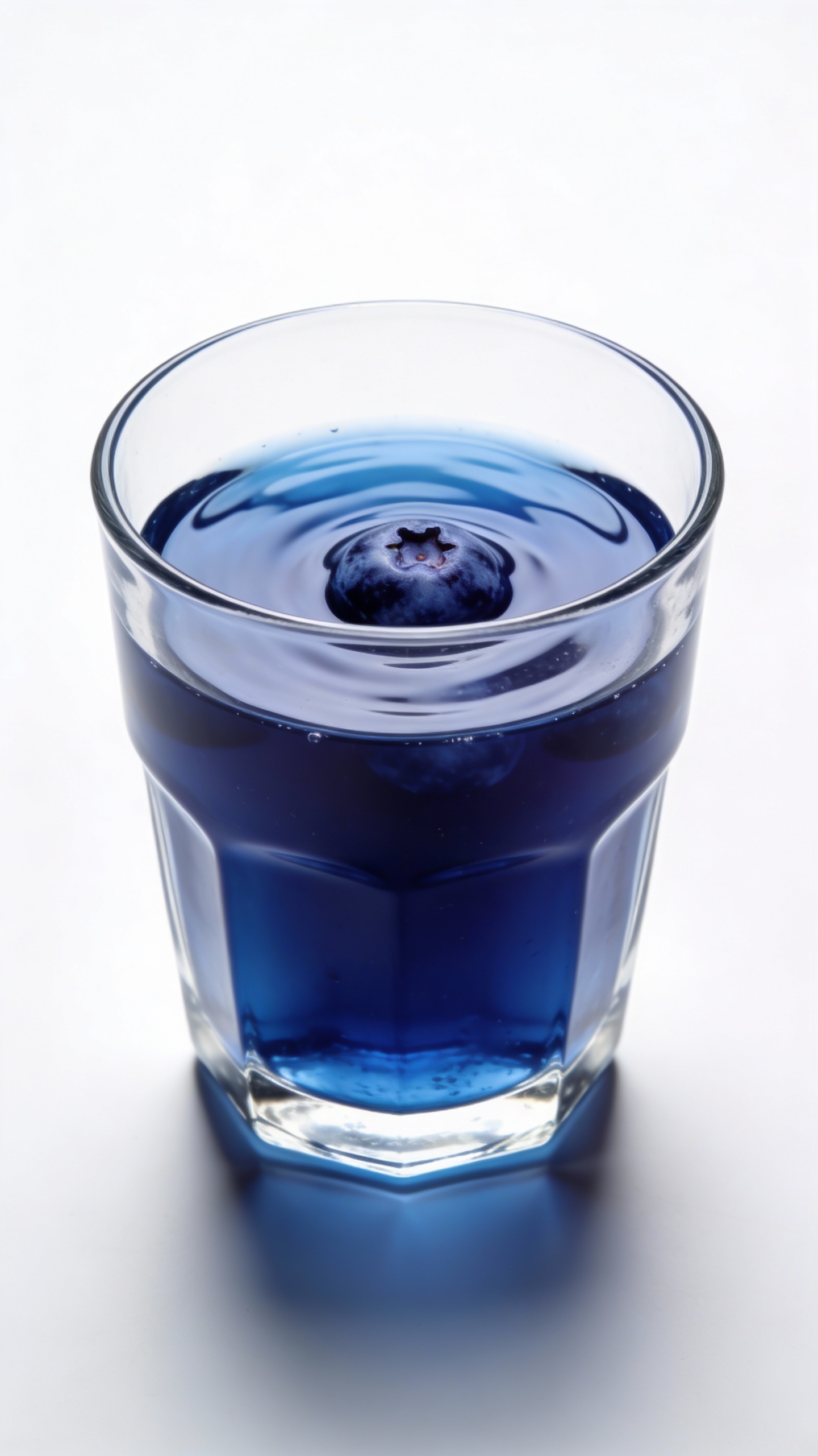 Blueberry juice in clear glass, white background, studio lighting
