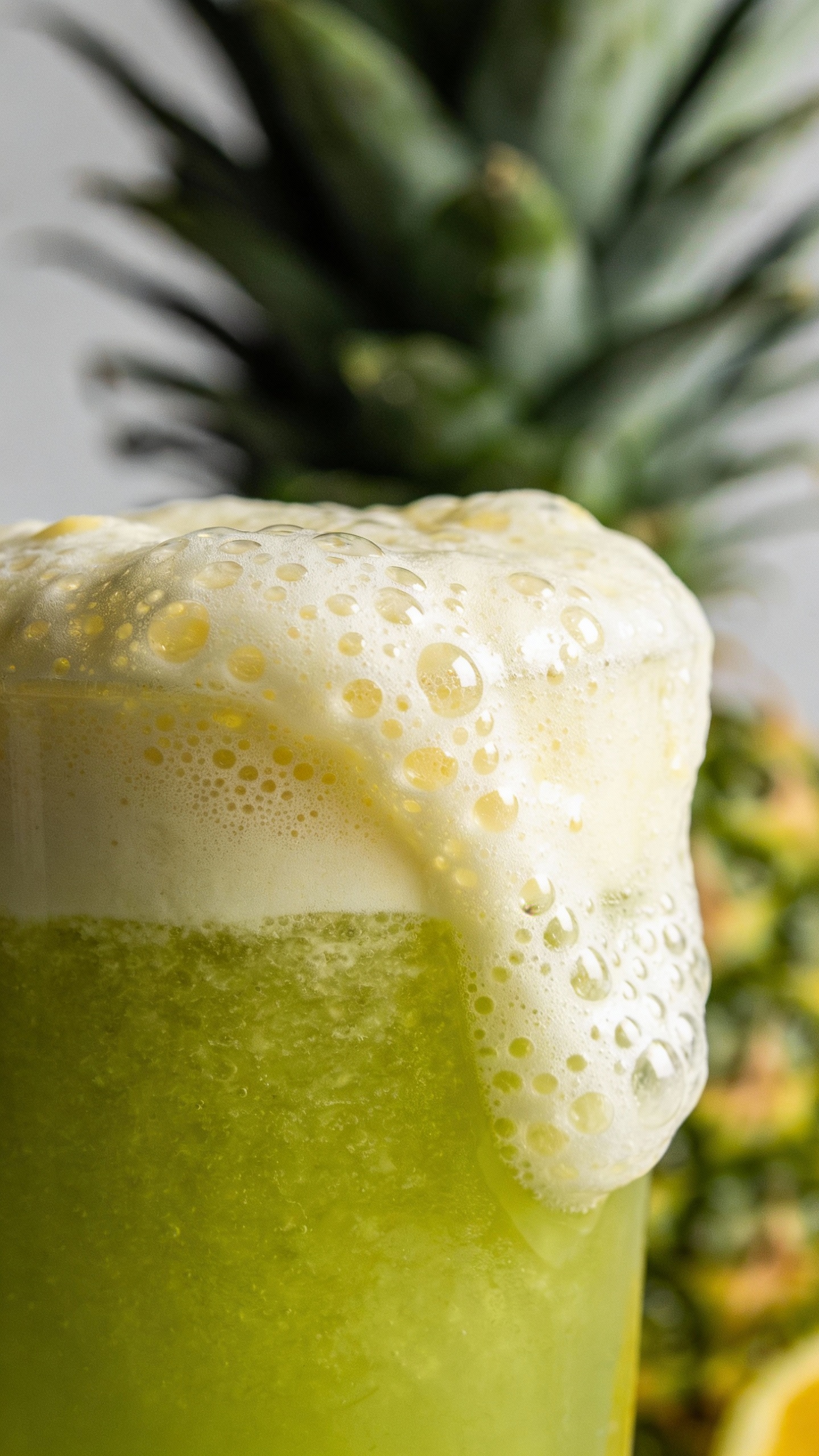 Close-up ginger lemon foam atop green pineapple juice
