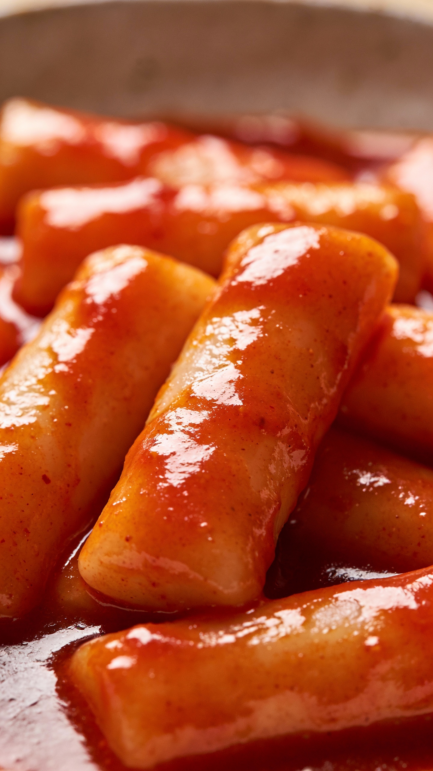 Close-up chewy tteok with fiery-red sauce sheen
