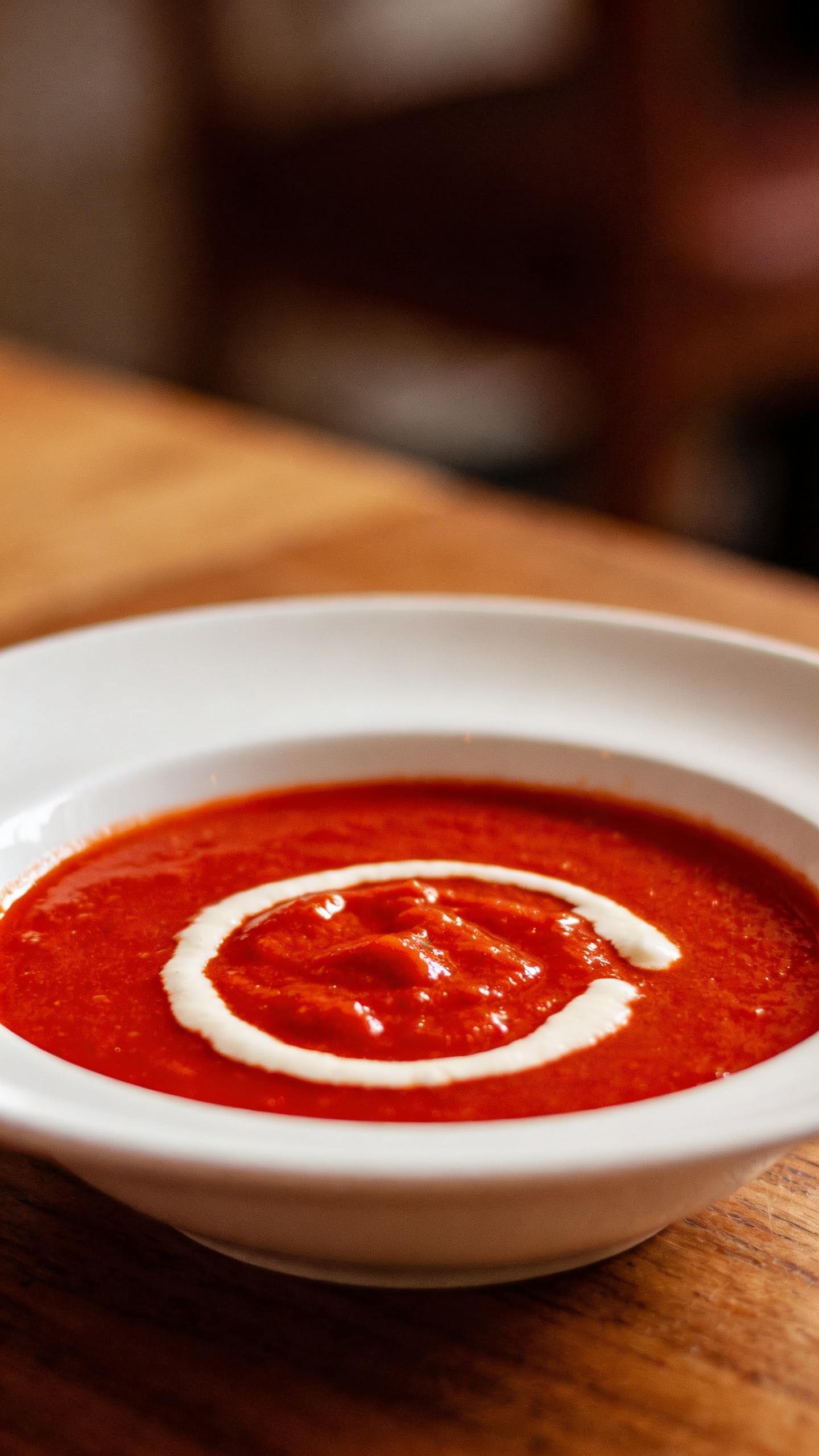 roasted red pepper soup in white bowl, cream swirl