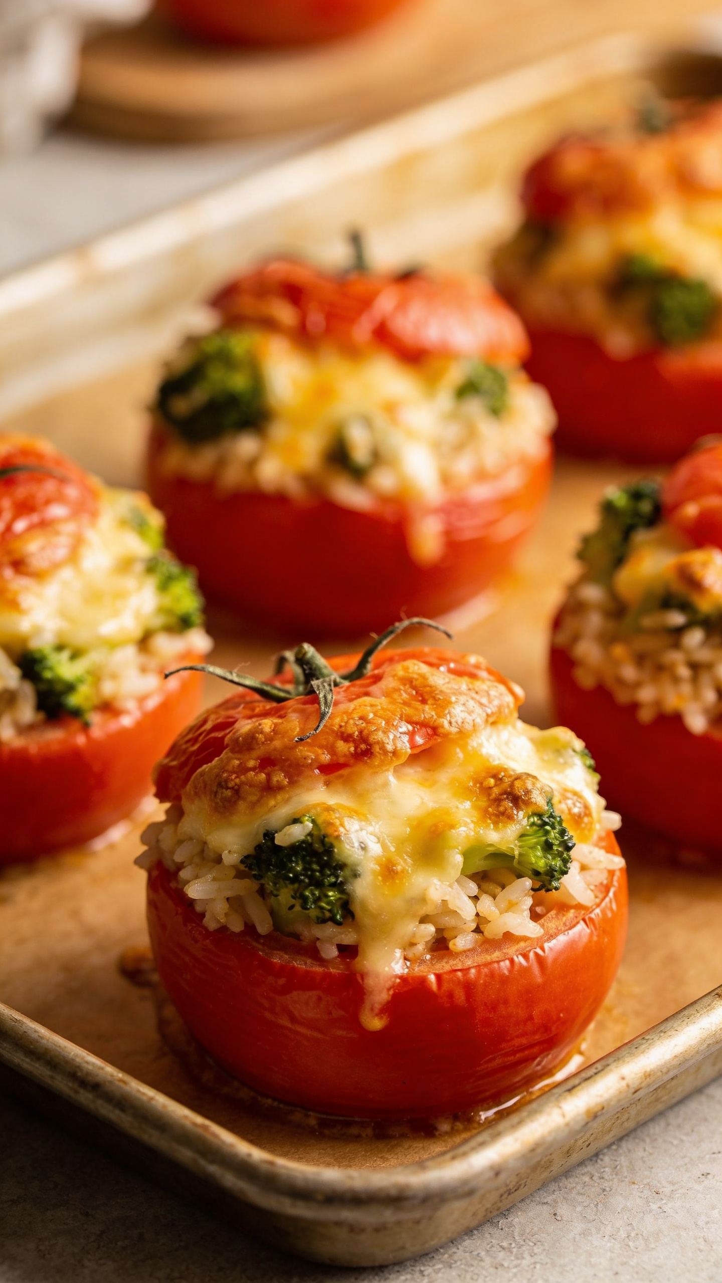 Cheesy broccoli rice stuffed tomatoes on baking sheet