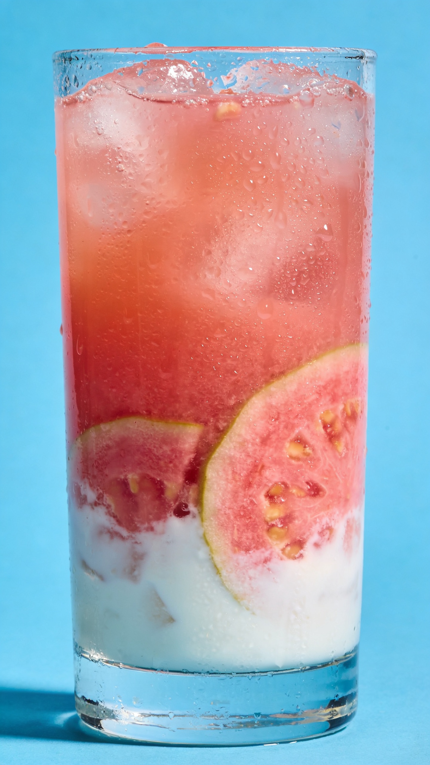 guava coconut punch in highball, condensation, bright backdrop