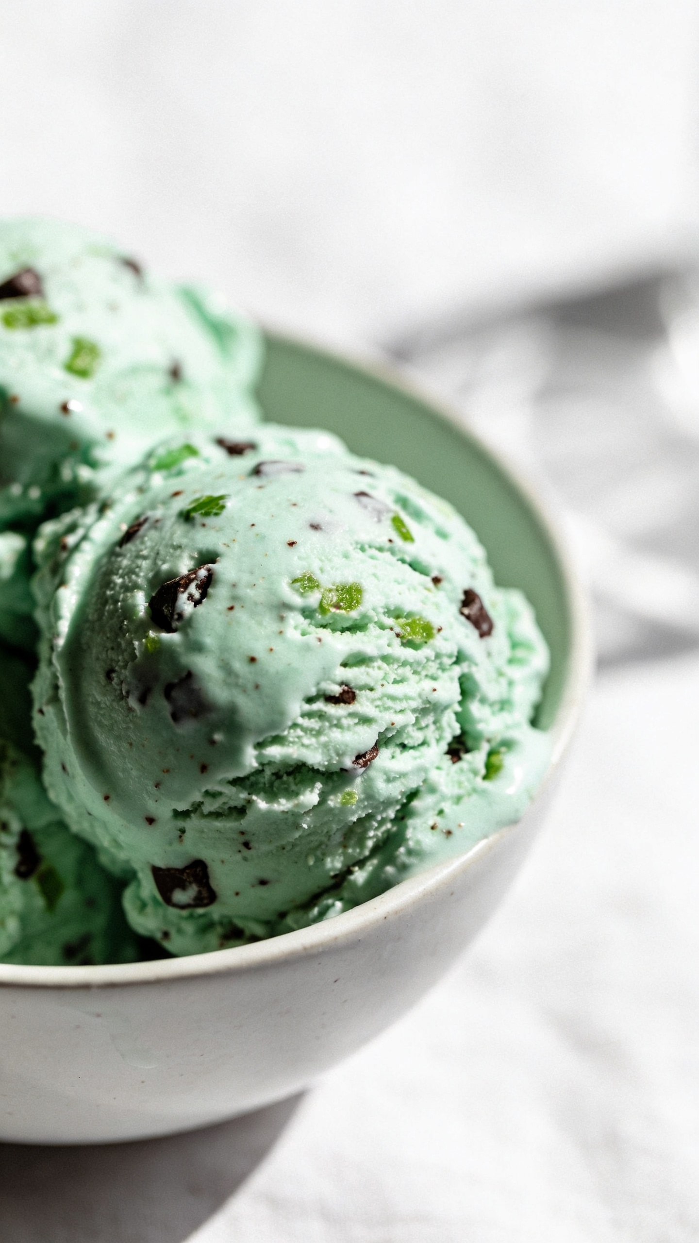 Mint chip ice cream scooped in white bowl, studio lighting